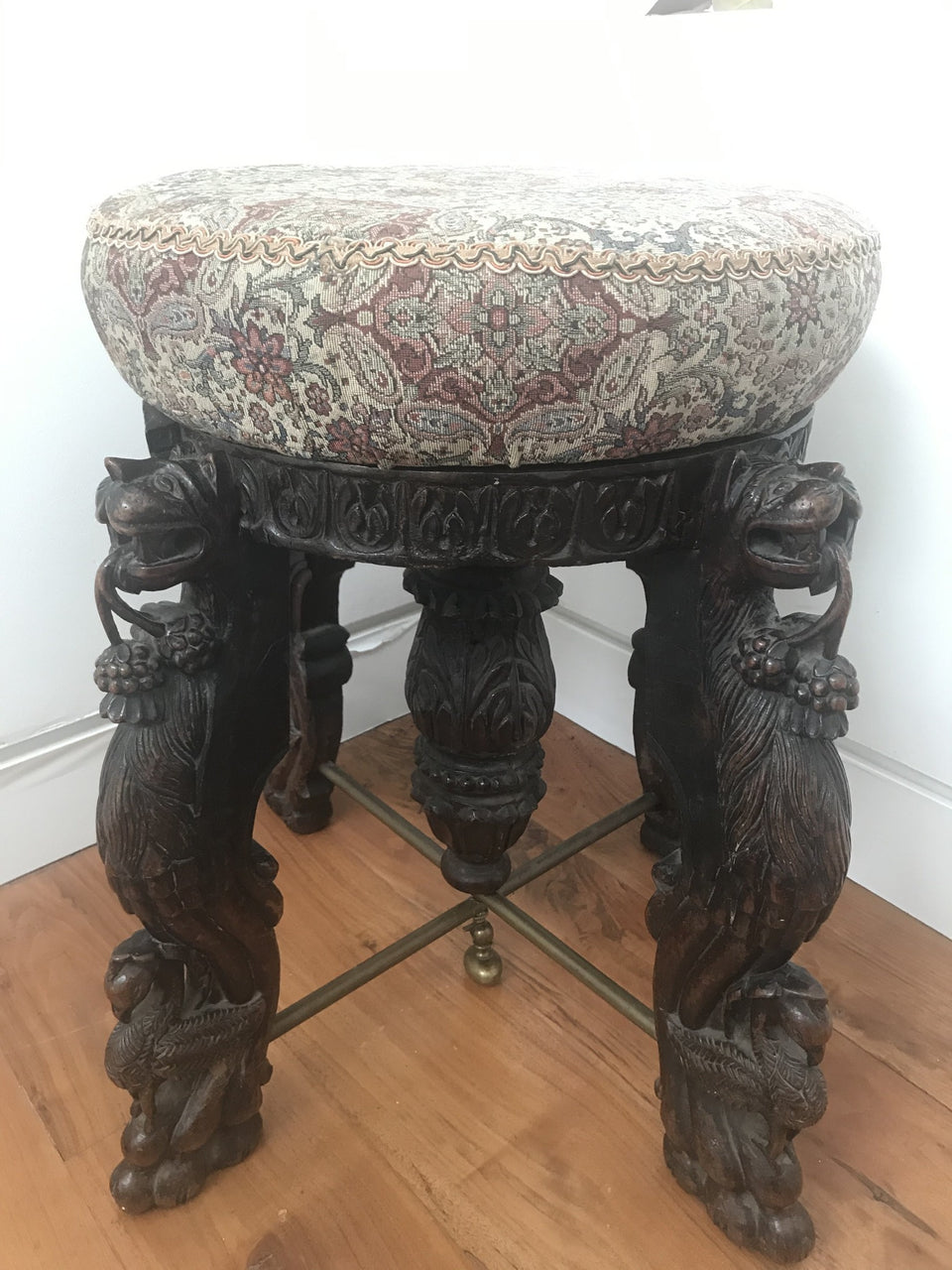 oriental stool with upholstered seat and four heavily carved legs with lions and birds and a carved centre column with brass stretchers